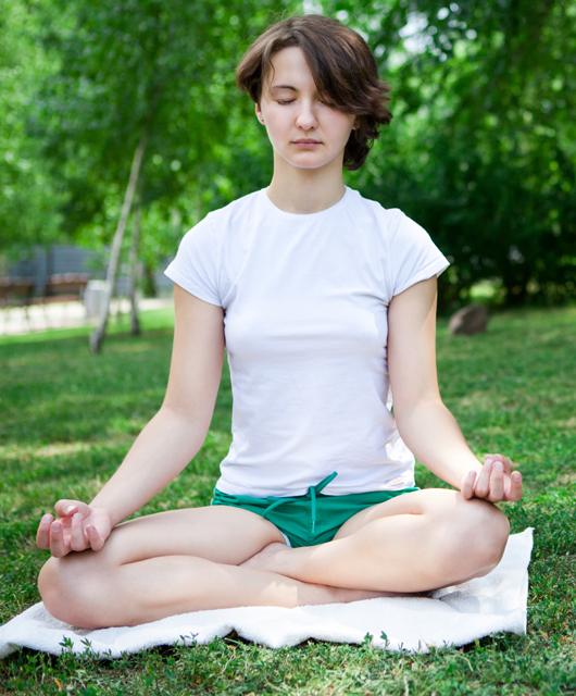 girl on grass meditating green shorts