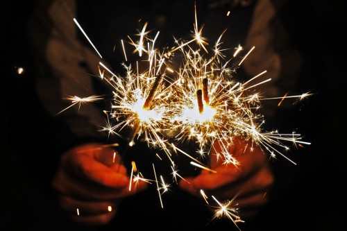 closeup of hands holding lit sparklers
