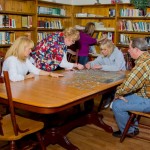 group of people doing a puzzle - Library Puzzle - St. Joseph Institute