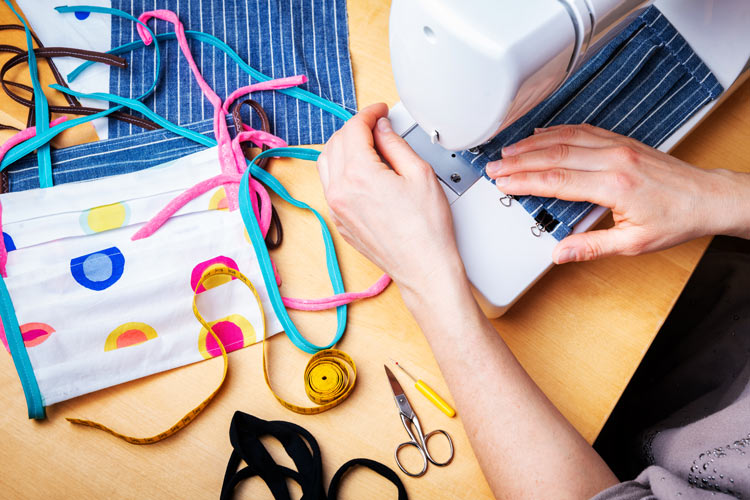 woman sewing homemade masks on sewing machine - stress