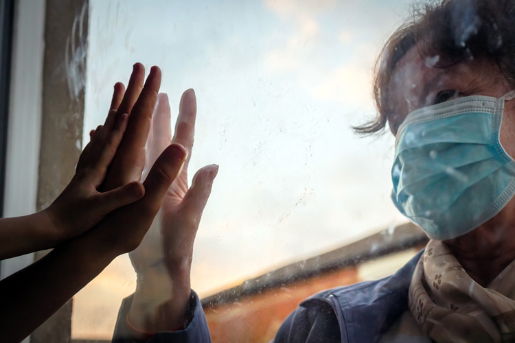 pandemic-related mental health challenges, older woman in face mask holding her hand up to child's hand on window pane - mental health and pandemic