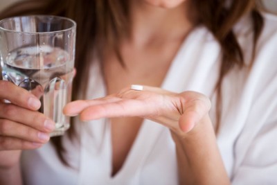 closeup of woman taking a white tablet - antidepressants and addiction recovery