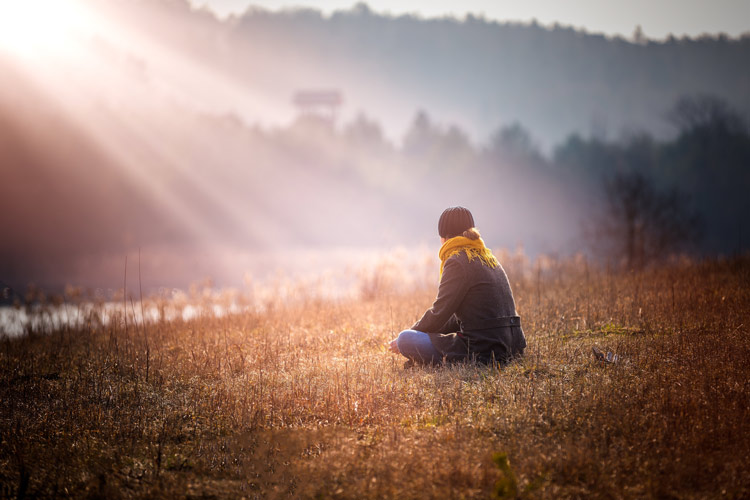 Addiction Treatment Programs in Pennsylvania at St. Joseph, person sitting alone in field on a foggy day with rays of sun shining down upon them - mental health